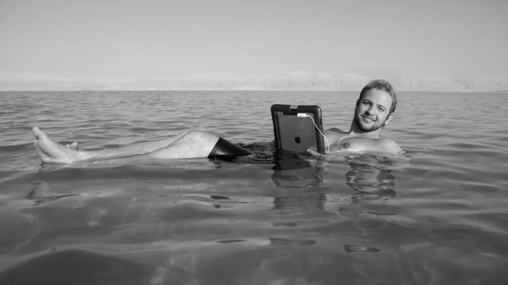 Man floating in water with tablet.
