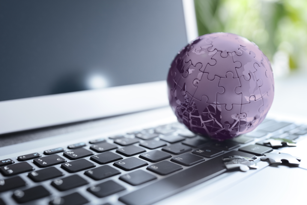 Lila Puzzle-Globus auf Laptop-Tastatur