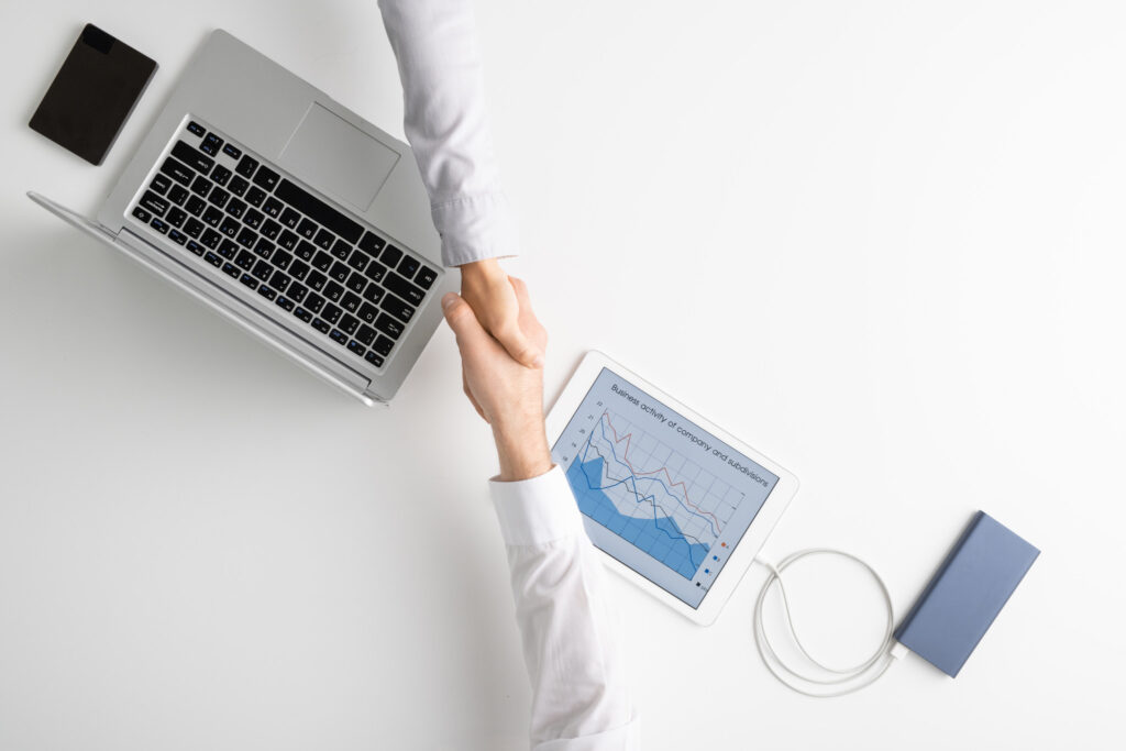 Händedruck über Laptop und Tablet mit Diagramm