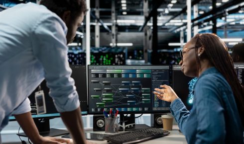 شخصان يتناقشان حول البيانات على شاشات الكمبيوتر.